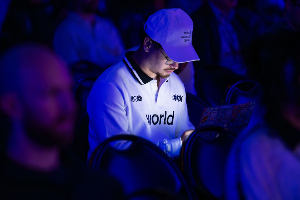 An attendee working on a laptop while seated in a blue-lit audience