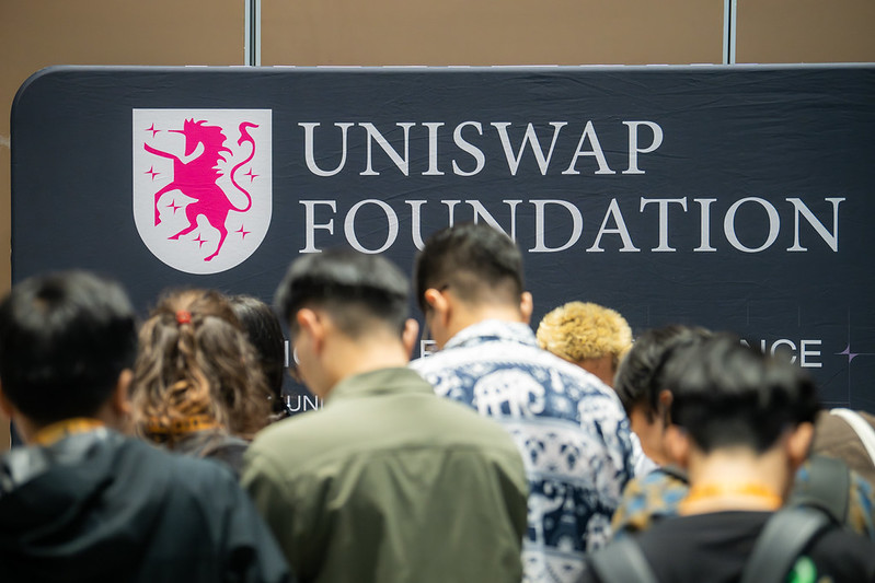 Attendees gathered in front of the Uniswap Foundation sponsor booth