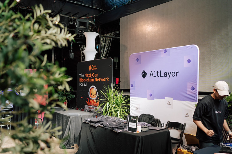 An event partner arranging merchandise at an AltLayer sponsor booth