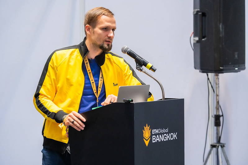 A speaker presenting from a laptop at an ETHGlobal Bangkok podium